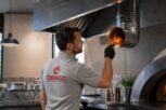 Tecnico Drago Group con polo grigia durante l’ispezione della canna fumaria in una cucina professionale